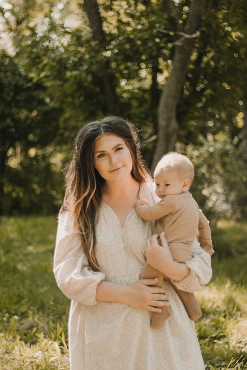 A mother holding her baby in a lush outdoor setting